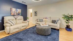 A living room with a beige sofa, a round ottoman, and a blue rug. - Peaceful Fairhope Getaway, 2 Mi to South Beach (Fairhope)