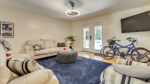 A living room with a sofa, ottoman, and a blue rug. A bicycle is leaning against the wall. - Peaceful Fairhope Getaway, 2 Mi to South Beach (Fairhope)