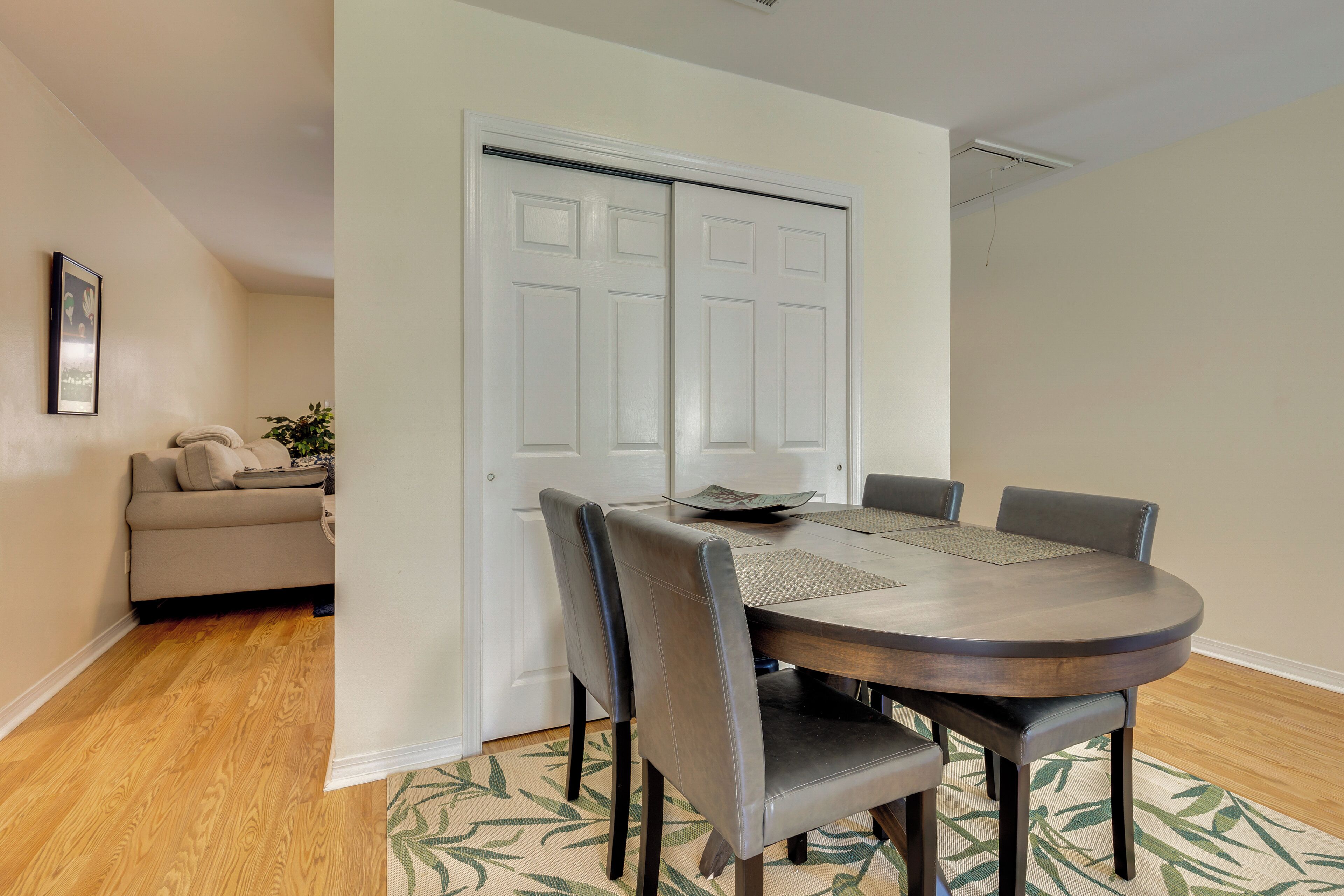 A dining area with a round table, four chairs, and a white door in the background.