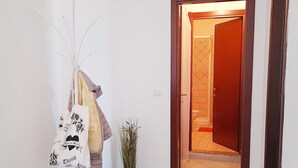 A hallway with a white wall, a wooden door, and a potted plant. - Affittimoderni Valledoria - Sa Turritta (Valledoria)
