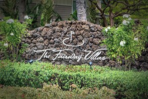 A landscaped area with a rock wall and a sign that reads 'The Fairway Villas.'