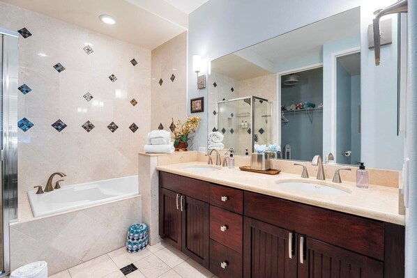 Un baño moderno con bañera, dos lavamanos, un espejo grande y cabina de ducha.