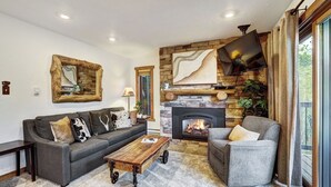 A living room with a stone fireplace, a sofa, a chair, and a coffee table. - Stylish and convenient to town and the slopes! Lances West 11 (Breckenridge)