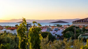 A coastal town with buildings, a clear sky, and a view of the sea and mountains. - Kent Otel Ayvalık (Ayvalik)