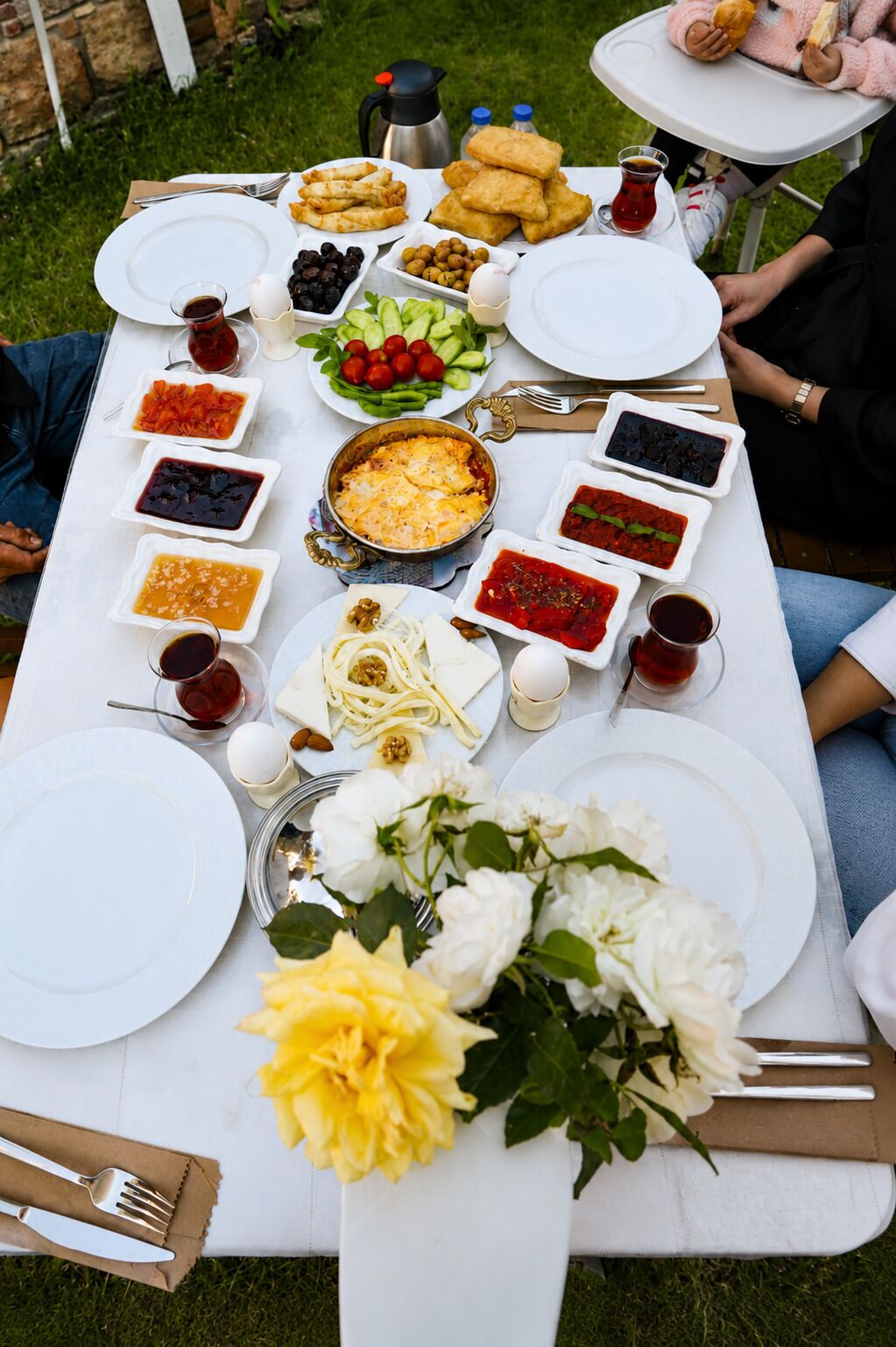 Un montaje para picnic con diferentes platos, una cafetera y una mesa con mantel blanco.