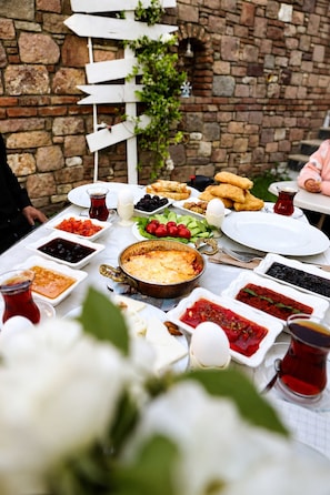 A table set with various dishes, a whiteboard, and a brick wall. - Kent Otel Ayvalık (Ayvalik)