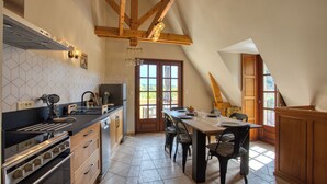 A kitchen with a large island, wooden beams, and a dining area with a table and chairs.