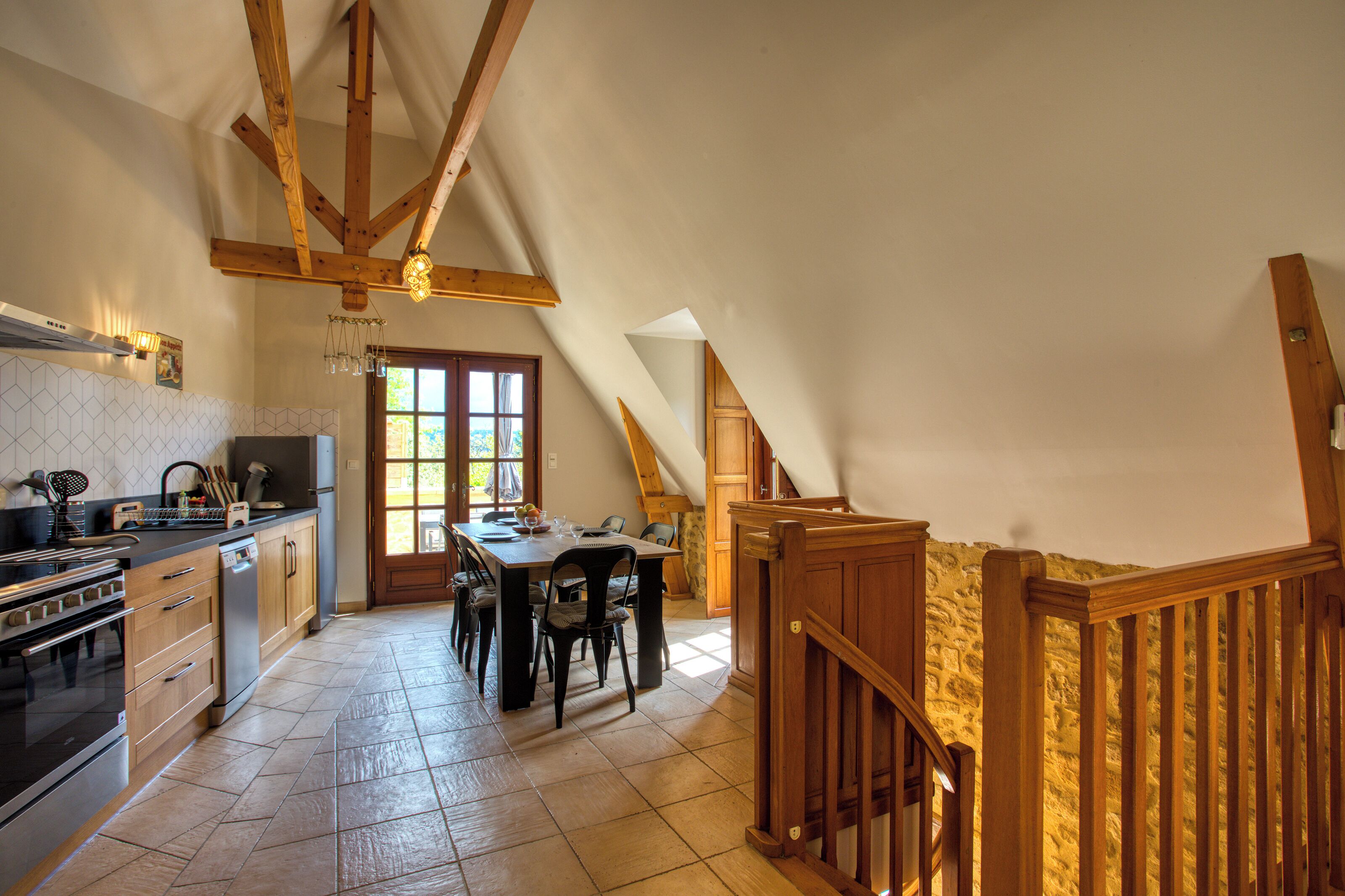 A kitchen with wooden beams, a dining table, and a staircase.