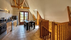 A kitchen with wooden beams, a dining table, and a staircase.