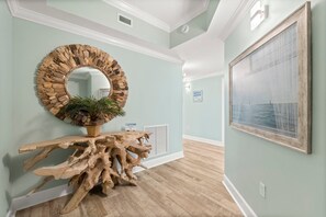 A hallway with a wooden console table, a mirror, and a framed painting.