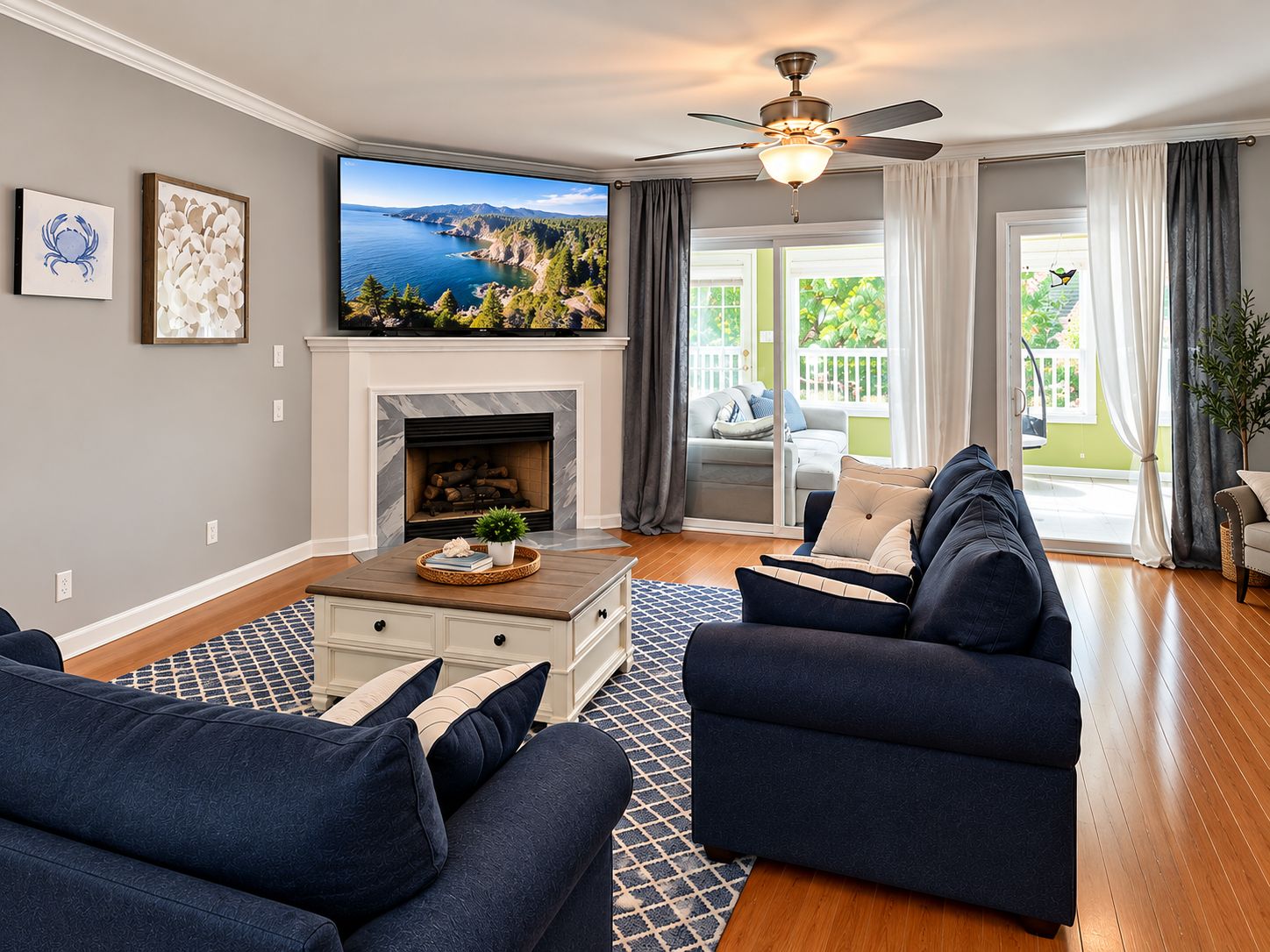 A living room with a fireplace, a television, and a view of a coastal landscape.