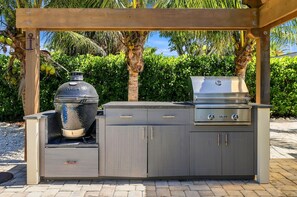 Una cocina exterior con una parrilla empotrada y una olla grande.