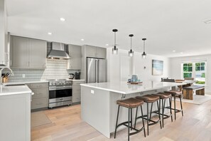 A modern kitchen with grey cabinets, stainless steel appliances, and a central island with bar stools.