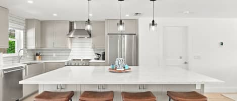 A modern kitchen with a large island, stainless steel appliances, and bar stools.