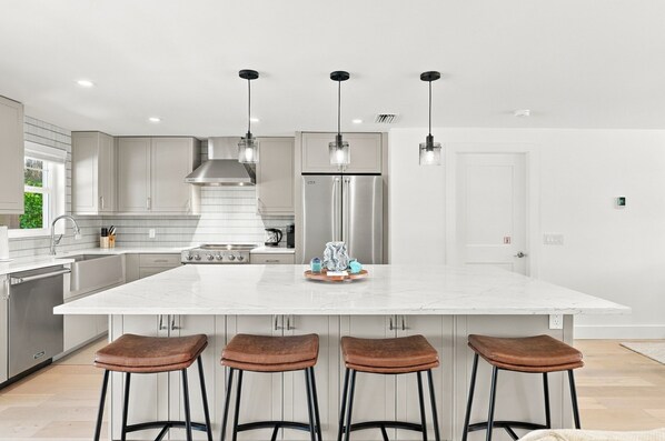 A modern kitchen with a large island, stainless steel appliances, and bar stools.