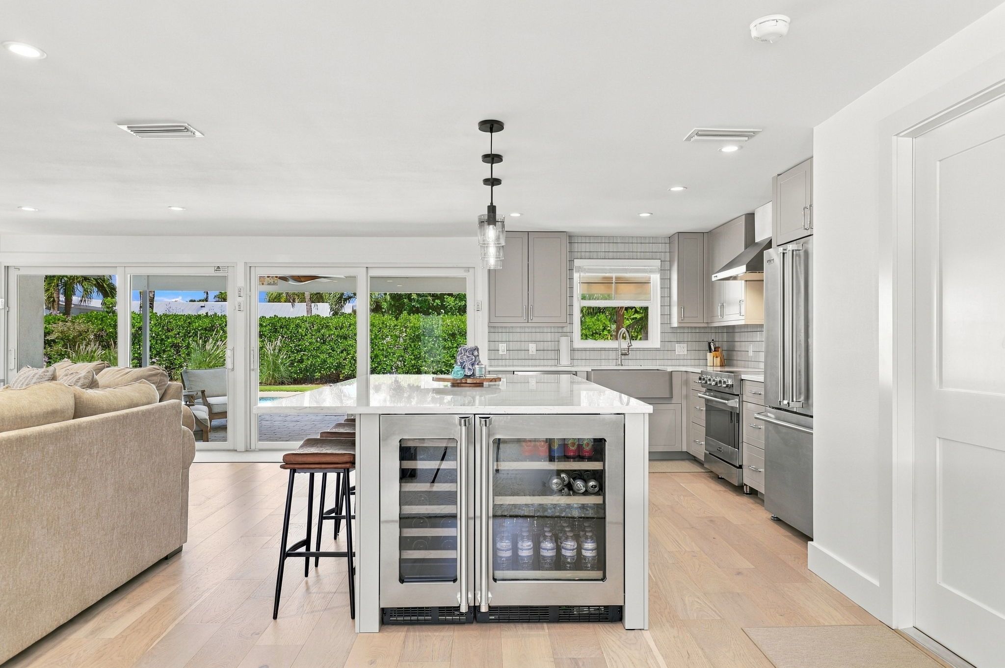 Une cuisine moderne dotée d’un îlot central, d’appareils électroménagers en acier inoxydable et offrant une vue sur un jardin luxuriant.
