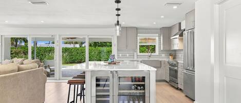 A modern kitchen with a central island, stainless steel appliances, and a view to a lush garden.