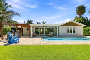 A modern house with a pool, outdoor seating, and a pergola.