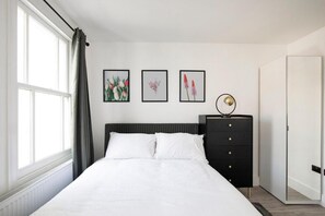 A bedroom with a bed, a dresser, and three framed floral pictures on the wall.