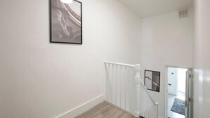 Un escalier avec une rampe blanche et un mur blanc.