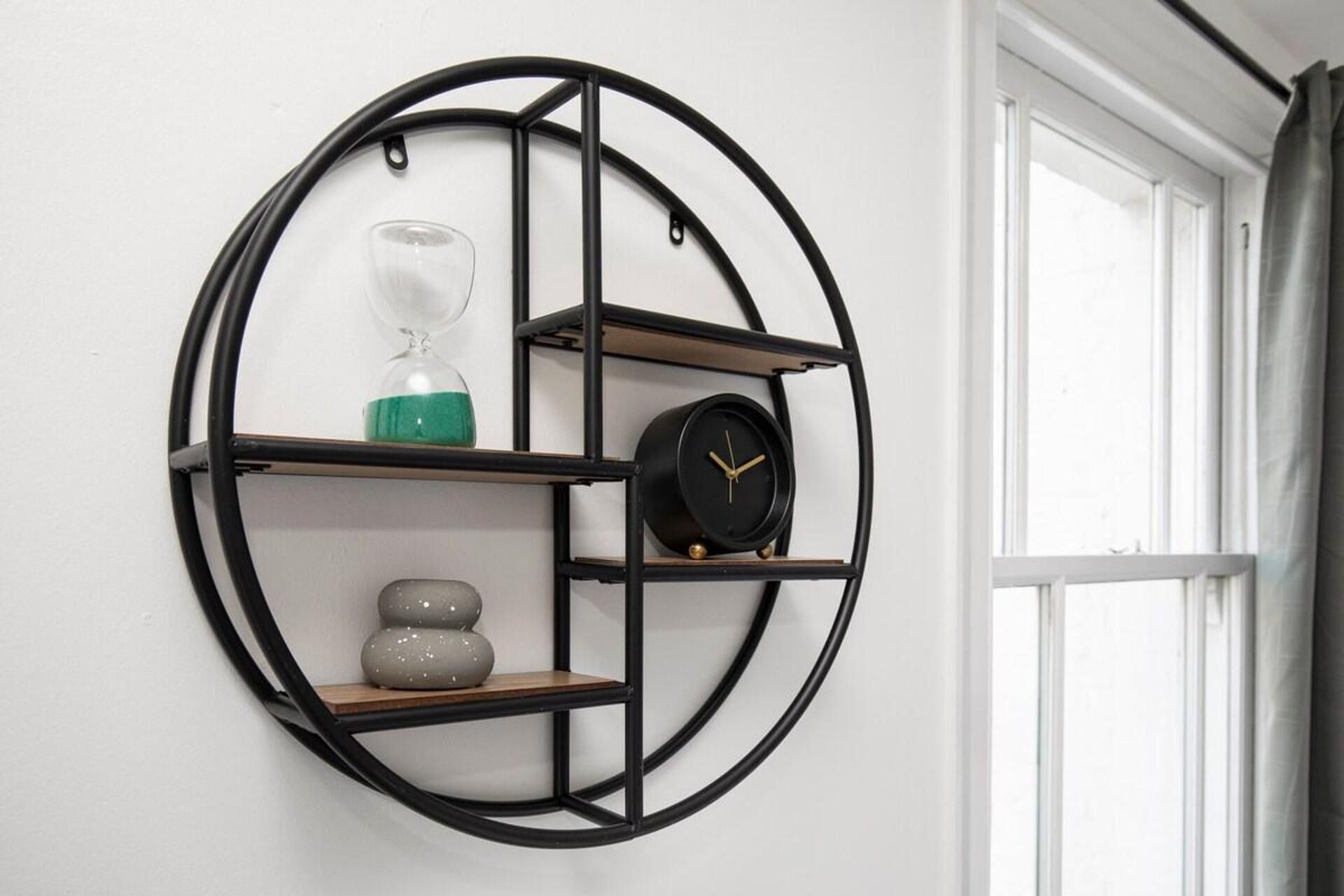 A circular wall-mounted shelf with a clock and decorative items.