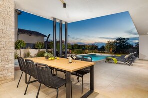 Une terrasse avec une piscine, un espace salon extérieur et une table avec des chaises.