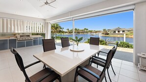 A modern kitchen with a large island, a dining area with a table and chairs, and a view of a body of water and greenery.