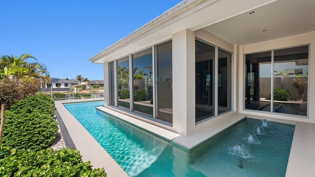 A modern house with a swimming pool, large windows, and a well-maintained garden.