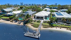 A coastal residential area with modern houses, a dock, and a clear view of the beach.