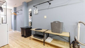A room with a wooden floor, a black cabinet, a wooden table with a basket, a mirror, and a vacuum cleaner. - DS DOUTONBORI 2 3F (Osaka)