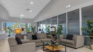 A modern lobby with sofas, a coffee table, and large windows offering views of the outdoors. - 3 Bed/2.5 Bath Perfect Family Home Bunk Beds 3 Bedroom Townhouse by RedAwning (Kissimmee)