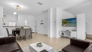 A modern living room with a brown leather sofa, a white coffee table, and a TV mounted on the wall. - 3 Bed/2.5 Bath Perfect Family Home Bunk Beds 3 Bedroom Townhouse by RedAwning (Kissimmee)