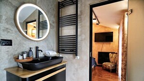 A modern bathroom with a black sink, a round mirror, and a towel rack. - Hotel Labiatan (Shkodër)