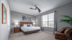 A bedroom with a bed, bedside tables, a ceiling fan, a window with curtains, and a plant. - Vista Cay Luxury Rhapsody 3 Bedroom Condo by RedAwning (Orlando)