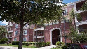 A multi-story residential building with a central entrance, balconies, and a parking lot. - Vista Cay Luxury Rhapsody 3 Bedroom Condo by RedAwning (Orlando)