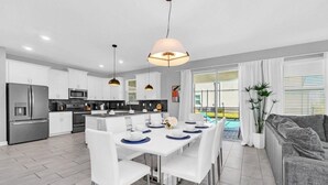 Une cuisine moderne avec des armoires blanches, des appareils en acier inoxydable et des luminaires suspendus.