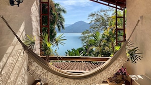 Eine Hängematte in einem Zimmer mit Blick auf einen See und Berge.