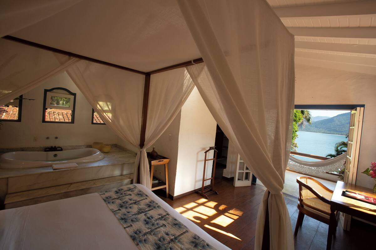 Ein Schlafzimmer mit einem großen Bett, ein Badezimmer mit einer Badewanne und Meerblick.