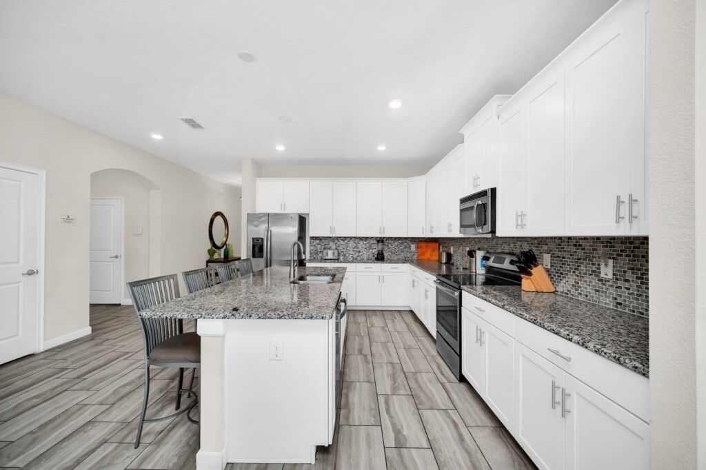 A modern kitchen with white cabinets, granite countertops, and a central island with seating.