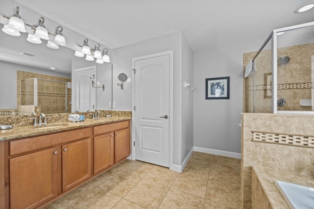 A modern bathroom with a large vanity, a shower area, and a walk-in closet.
