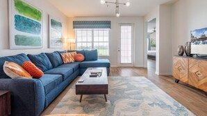 Una sala moderna con un sofá azul, una mesa de centro de madera y una alfombra estampada.