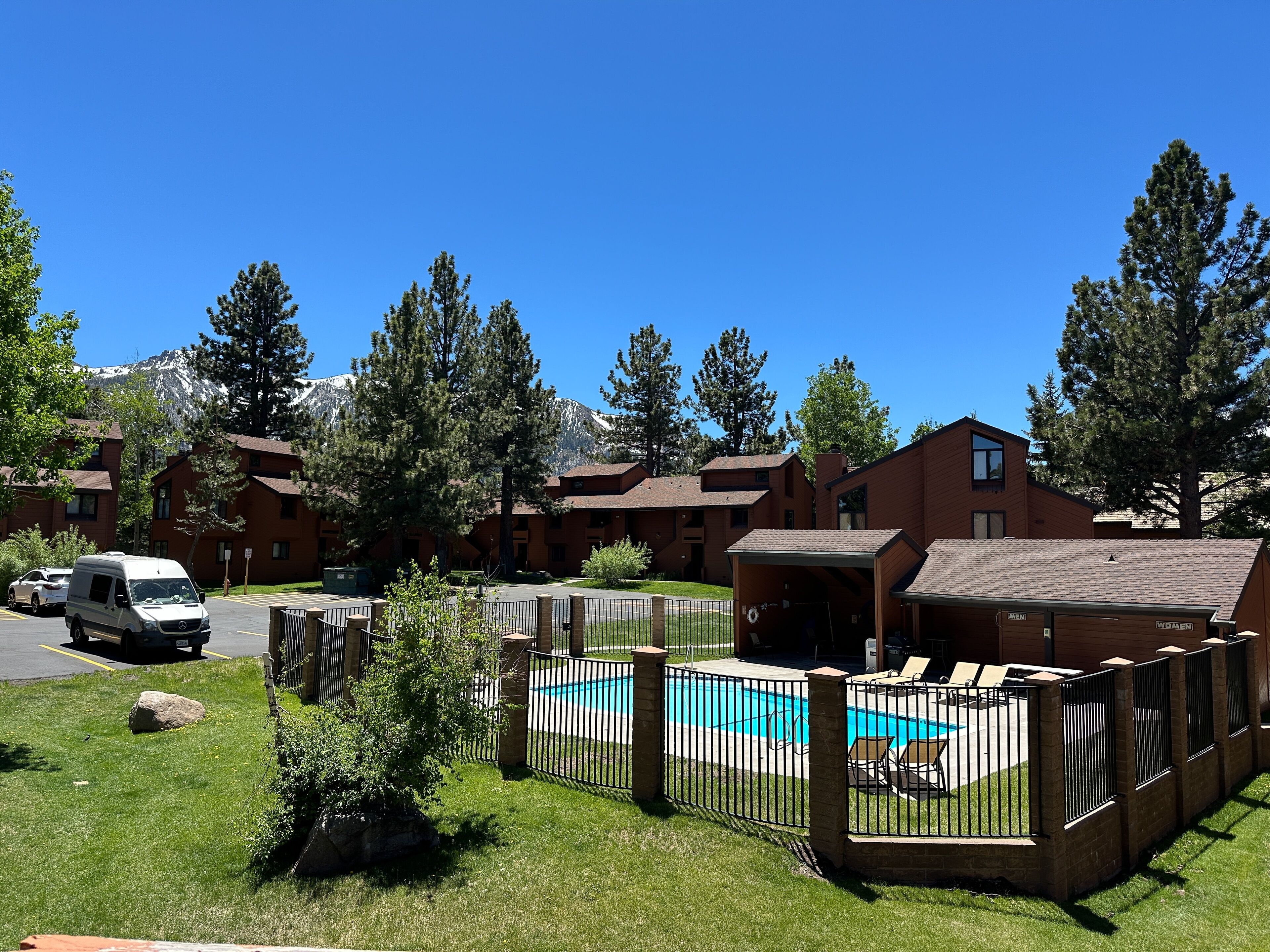 A residential area with a swimming pool, fenced patio, and multiple buildings.