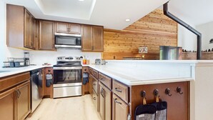 A modern kitchen with wooden cabinets, stainless steel appliances, and a white countertop. - Forest Creek #16 2 Bedroom Condo by RedAwning (Mammoth Lakes)