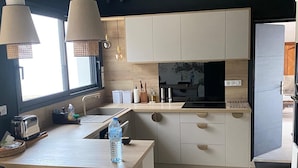 Eine moderne Küche mit einer zentralen Kochinsel, Holzschränken und Pendelleuchten.
