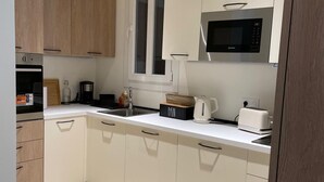 A modern kitchen with white cabinets, a microwave, a coffee maker, and a toaster. - Newly renovated apartment in Nice- with AC and 10 min walk to the beach! (Nice)