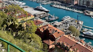 A coastal cityscape with a marina filled with boats, surrounded by densely packed buildings with red-tiled roofs. - Newly renovated apartment in Nice- with AC and 10 min walk to the beach! (Nice)