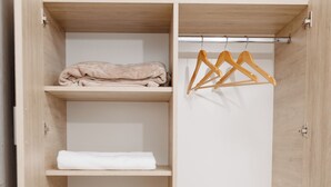 Une armoire en bois dotée de plusieurs étagères, d’une tringle et de tiroirs.