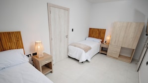 Une chambre avec deux lits, une armoire et des tables de chevet avec des lampes.