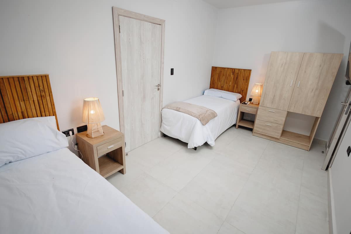 Een slaapkamer met twee bedden, een kledingkast en nachtkastjes met lampen.