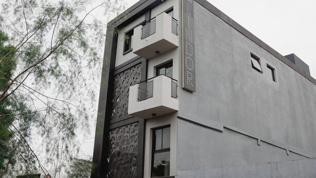 Un hôtel moderne à la façade grise, doté de balcons et d’un mur dont le motif rappelle la pierre.